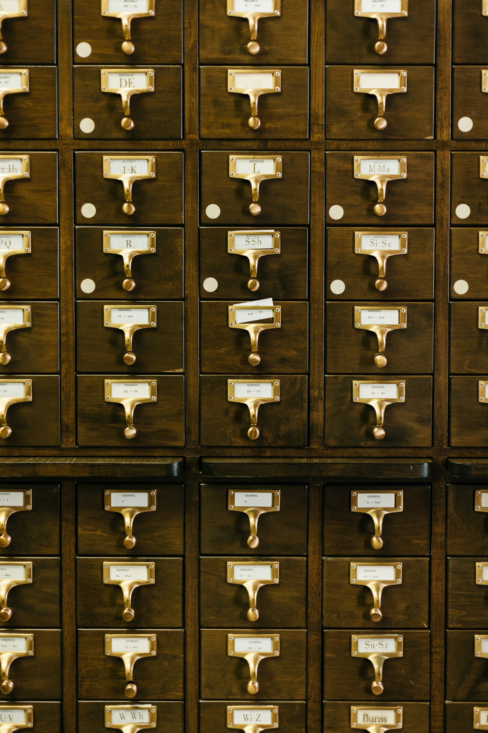 Wall of wooden library card-catalogue drawers with brass label holders